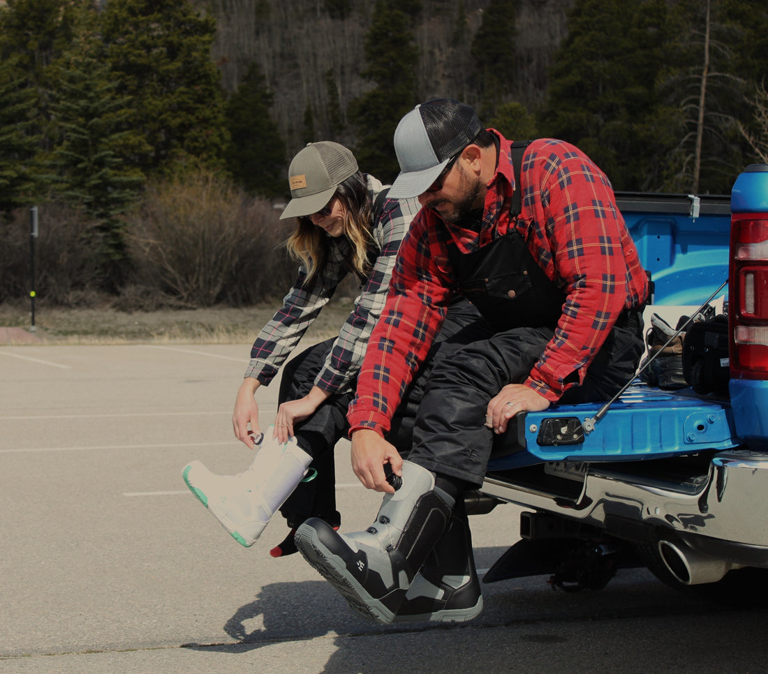 Two people trying on snowboard boots