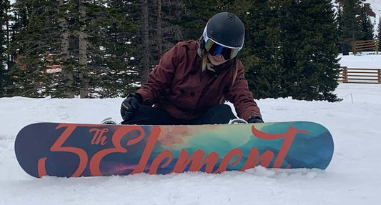 Woman strapping into snowboard