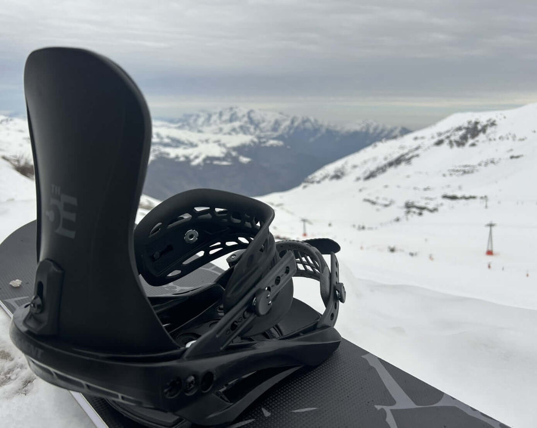Snowboard binding on snowboard with mountains in the background